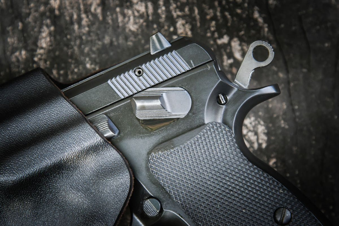A close-up view of a dark handgun, possibly a Sig Sauer M18 or P320, nestled in a black leather holster, highlighting critical holster safety features like trigger guard protection and retention for concealed carry.