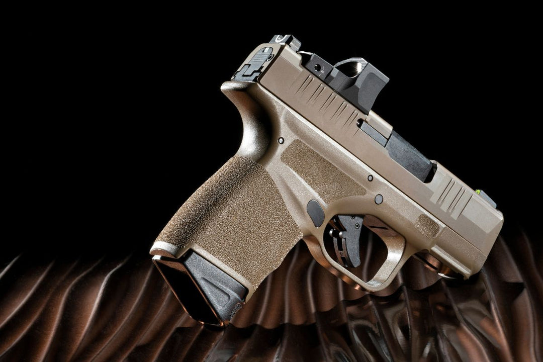 Micro-compact 9mm pistol with optic mounted, displayed on a dark, textured background