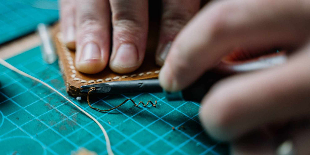 Close-up of hands stitching premium brown leather, highlighting the detailed development process behind Urban Carry’s leather holsters.