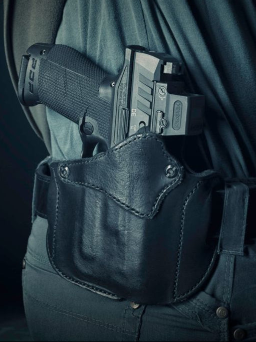 Close-up of a handgun secured in a black Urban Carry leather holster on a belt.