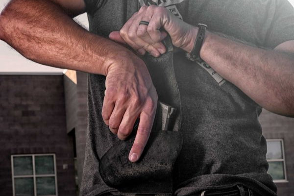 Man drawing a concealed handgun from an Urban Carry holster worn inside the waistband.
