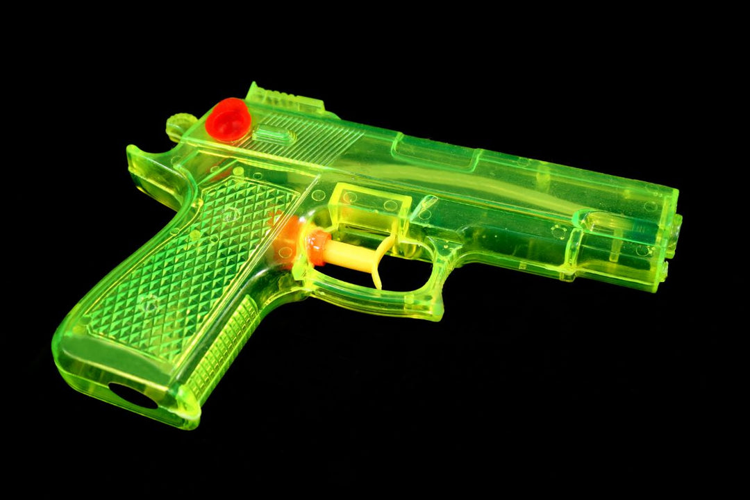 Bright green and yellow toy gun on a black background, representing the lighter, humorous side of concealed carry culture.