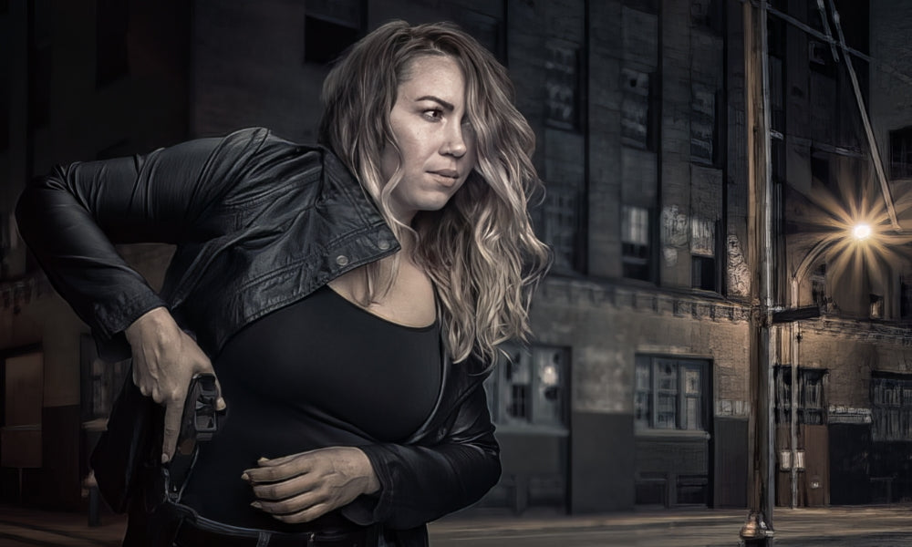 Woman drawing a concealed handgun from her waistband in an urban setting at night.