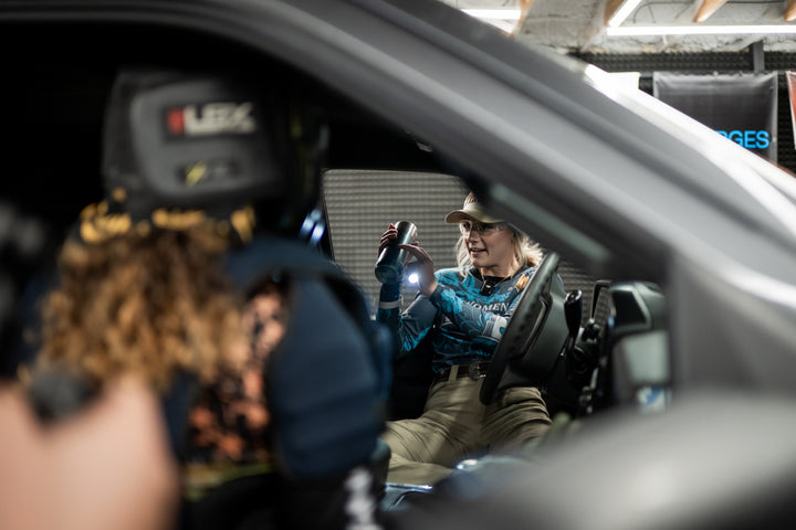 Person inside a car with filming equipment and a camera crew.