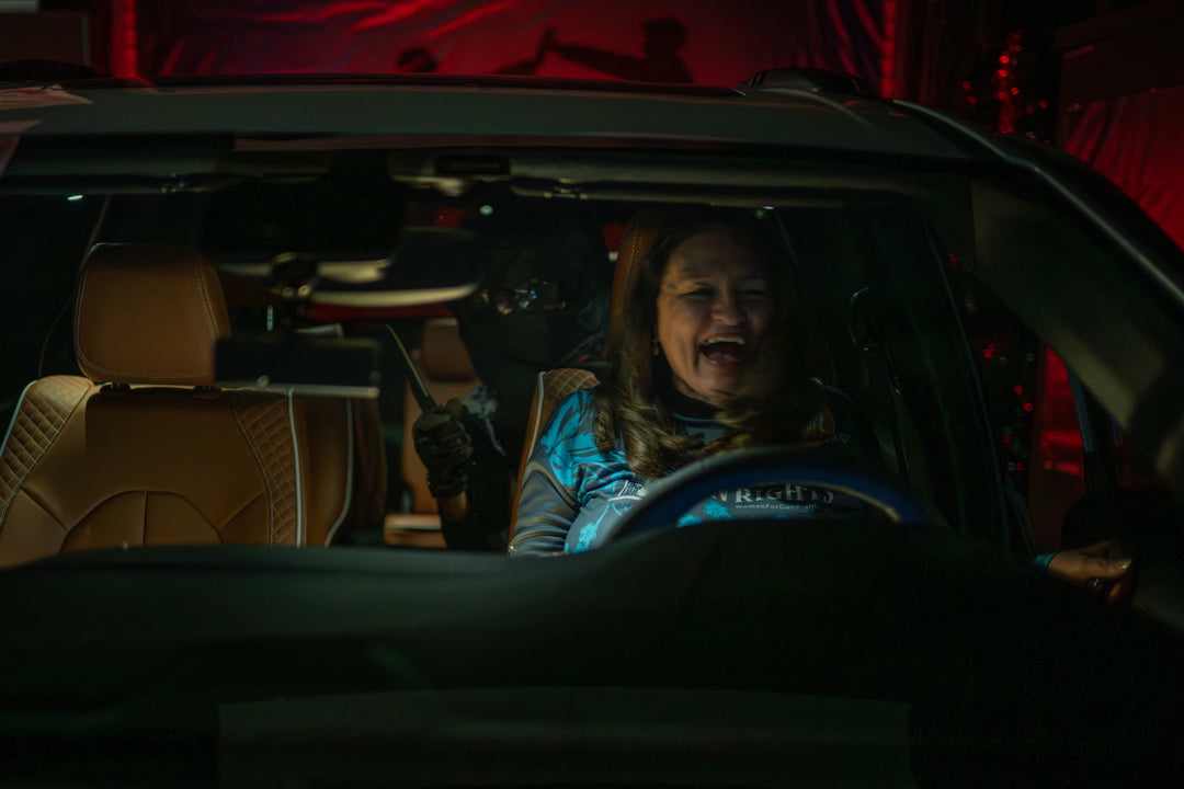 Woman inside a car with a dark interior, with a big smile on her face.