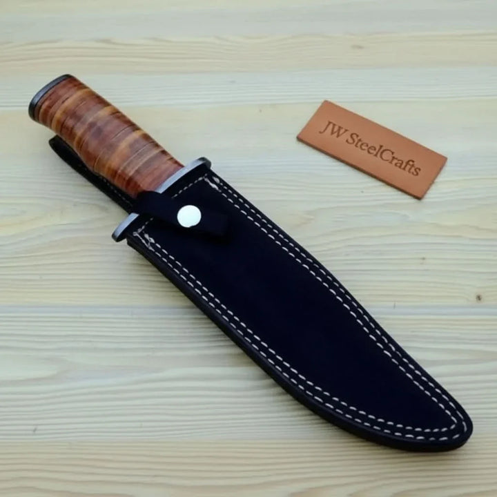 Knife with wooden handle and black sheath on a wooden surface with 'JW SteelCrafts' branding.