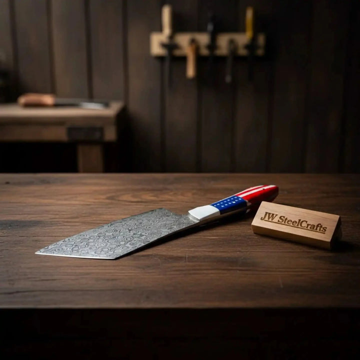 Cleaver knife with a decorative blade and american flag handle on a wooden block, branded 'JW SteelCrafts'.