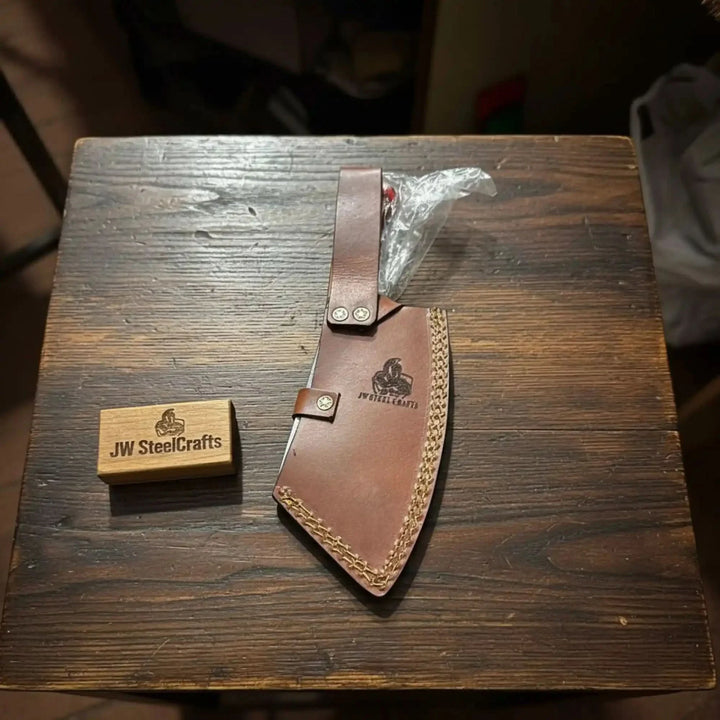 Cleaver knife in leather sheath on a wooden block, branded 'JW SteelCrafts'.