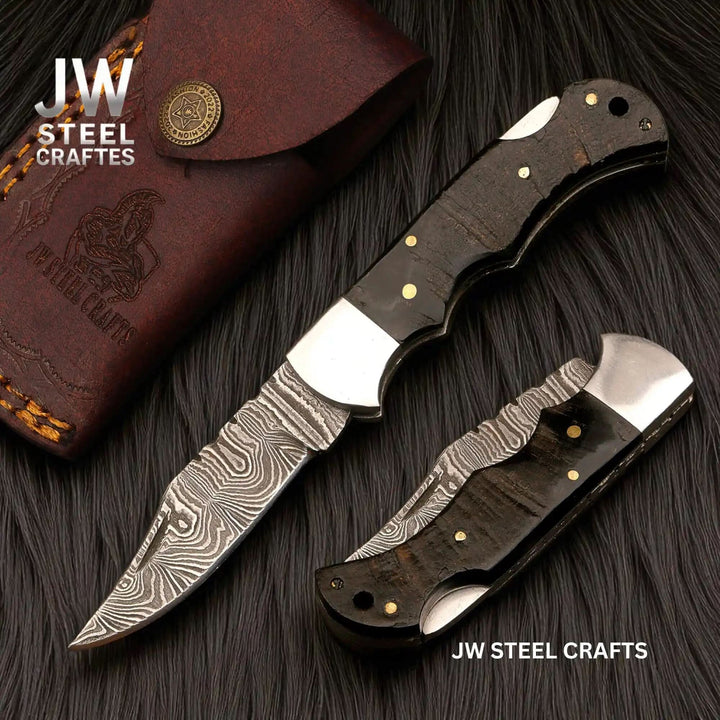 Two folding knives with wooden handles and a leather case on a dark surface, branded 'JW Steel Crafts'.