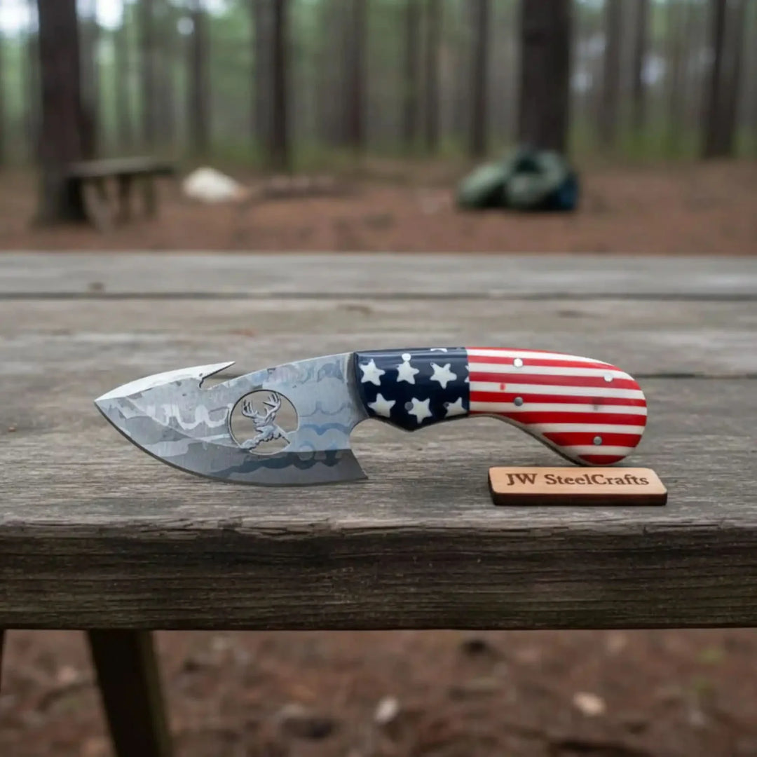 Knife with American flag handle on a wooden surface, next to a 'JW SteelCrafts' logo.