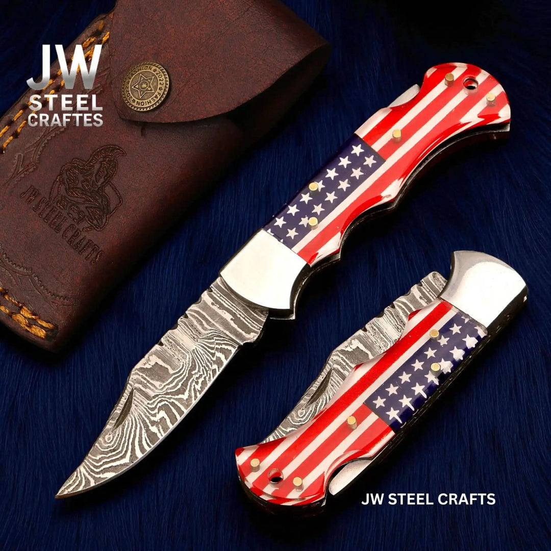 Two knives with American flag design on a blue surface, branded 'JW Steel Crafts'.