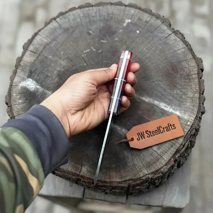 Hand holding a knife with a 'JW SteelCrafts' tag on a wooden log