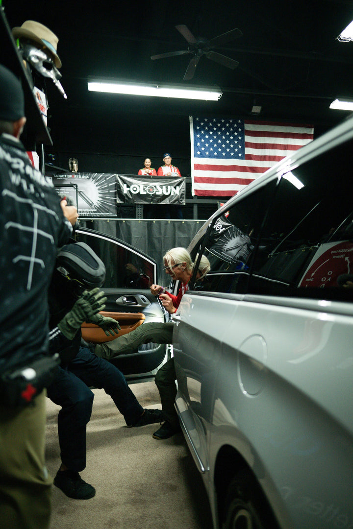 Person getting into a car with an American flag and 'Folkmun' banner in the background